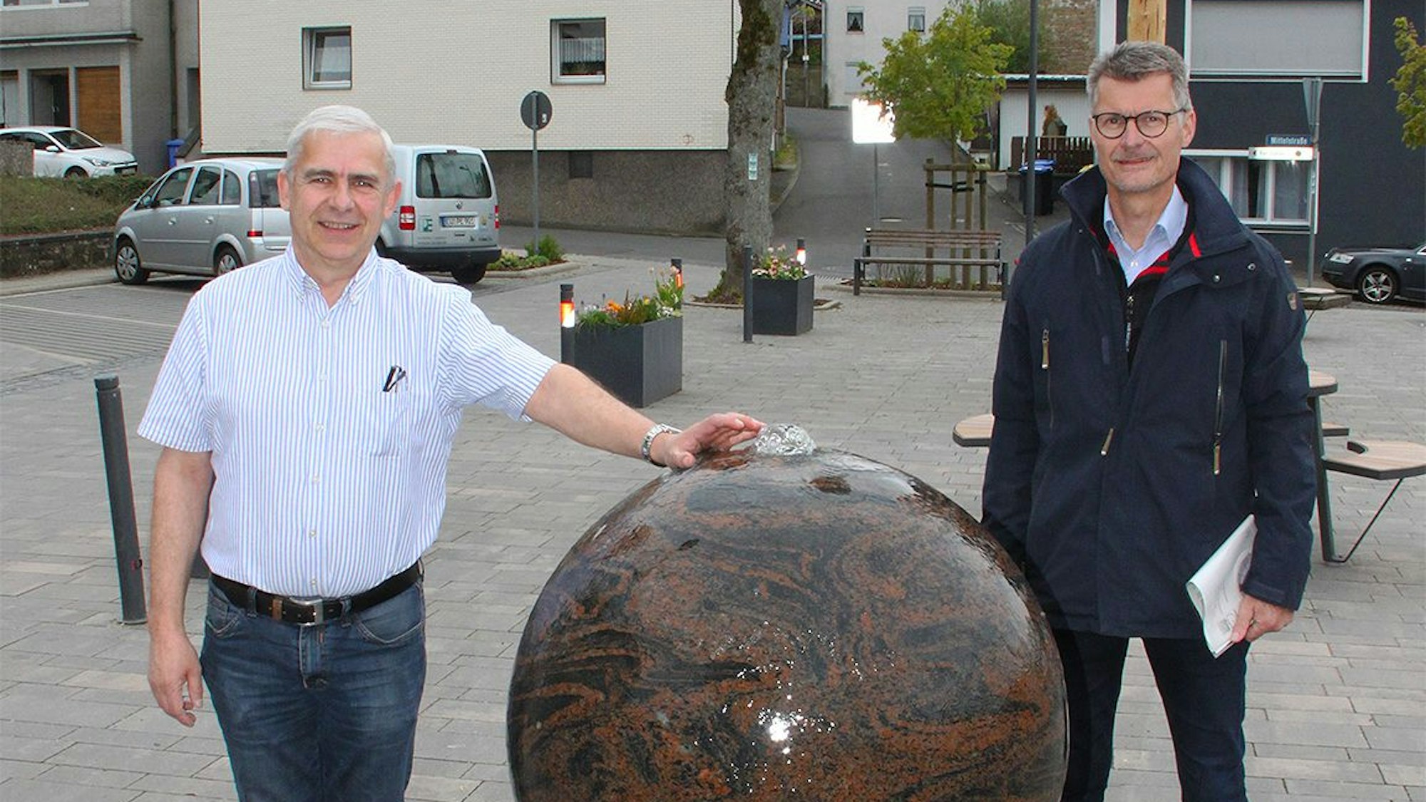Es sind die beiden Männer mit dem Kugelbrunnen zu sehen.