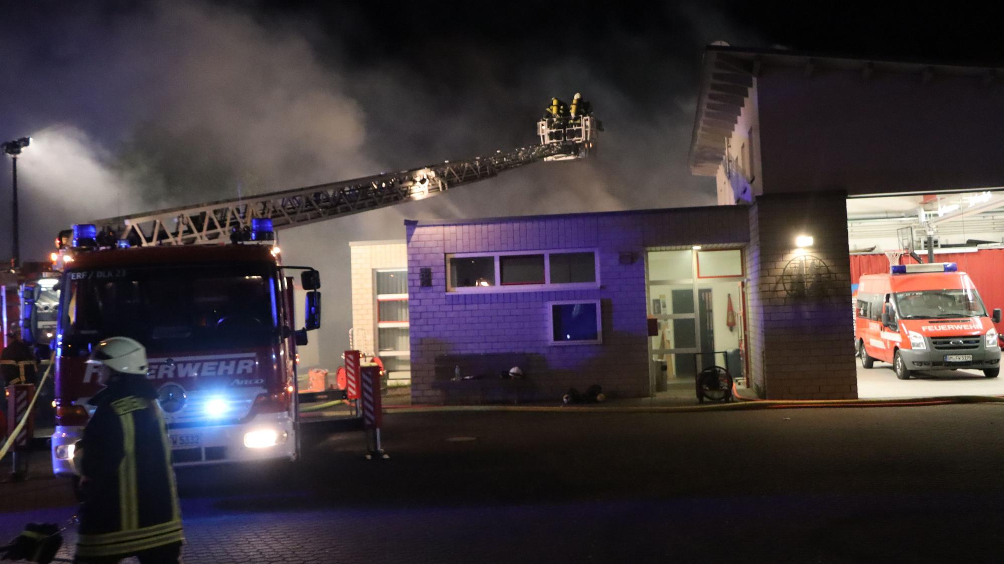 Auf dem Kran eines Feuerwehrautos befinden sich zwei Feuerwehrmänner im Einsatz.