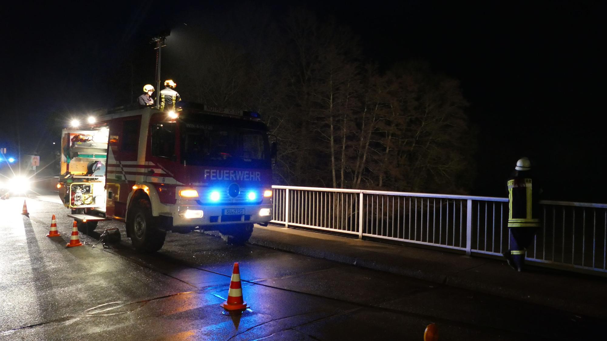 Ein Feuerwehrauto steht an einer mit Hütchen abgesperrten Brücke im Dunkeln auf der Straße. (Symbolbild)
