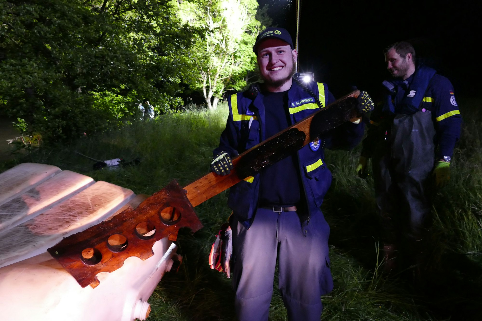Ein Feuerwehrmann neben einem der Tanks hält grinsend einen Bierhalter hoch.