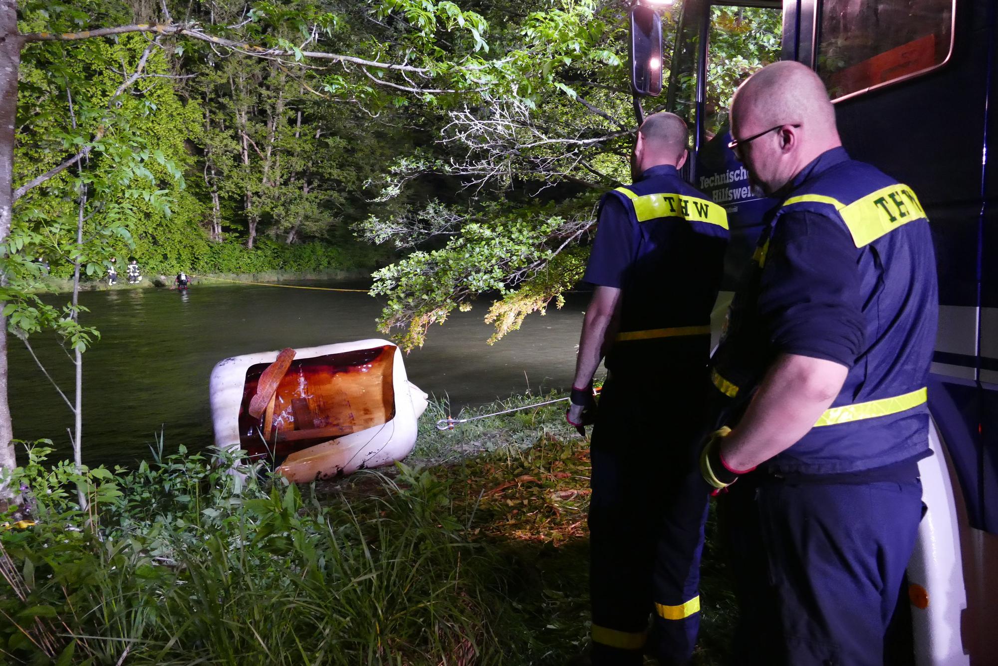 Zwei Feuerwehrmänner überwachen einen Tank, der mittels eines Hakens ans Ufer der Sieg gezogen wurde.