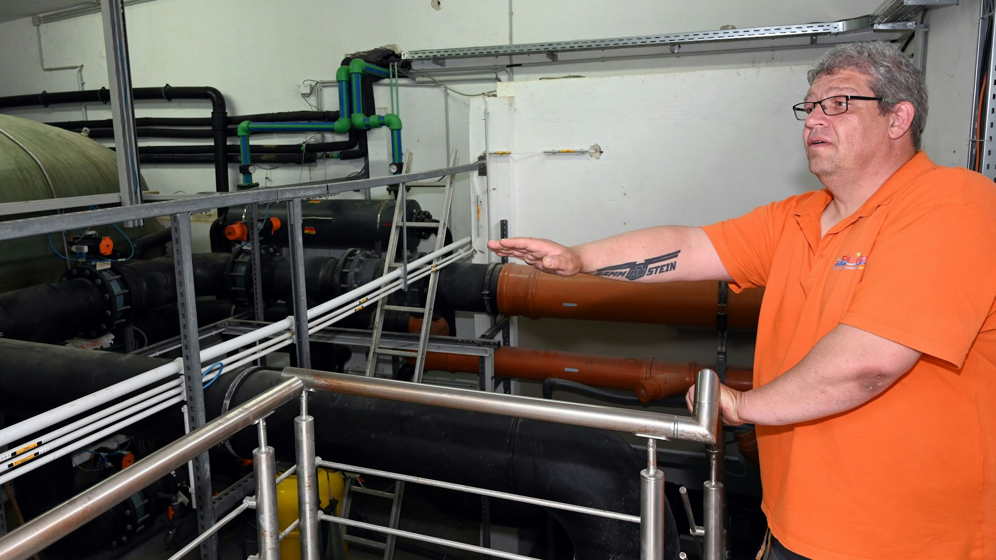 Ein Mann steht inmitten von Maschinen und Anlagen in den Katakomben eines Schwimmbades.