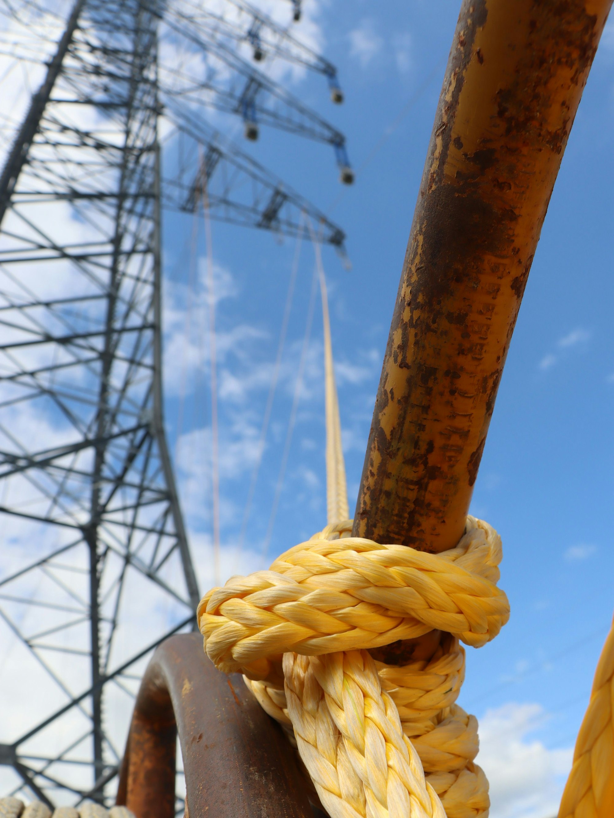 Ein geknotetes, kräftiges Seil reicht von einer Verankerung im Boden bis hoch auf einen Strommast.