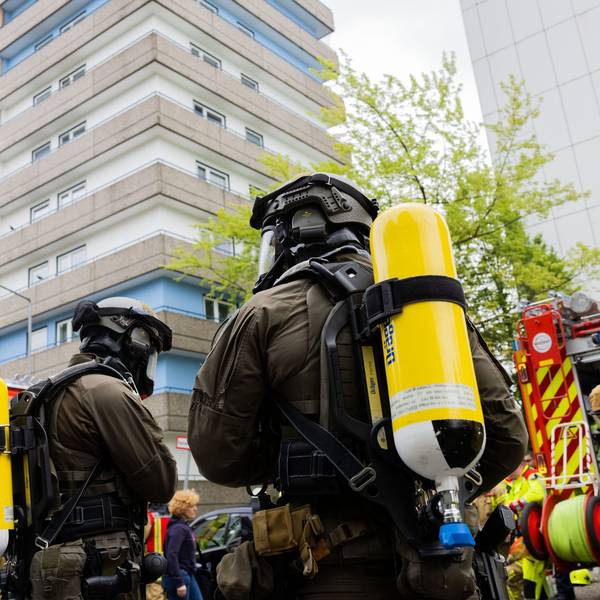 11. Mai: Polizeibeamte mit Gasmasken und Feuerwehrleute stehen vor dem Hochhaus in Ratingen, wo ein 57-Jähriger bewusst eine Explosion herbeigeführt haben soll.