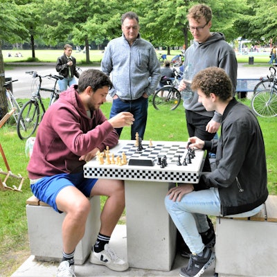 Zwei Männer sitzen im Inneren Grüngürtel vor einem Schachbrett.