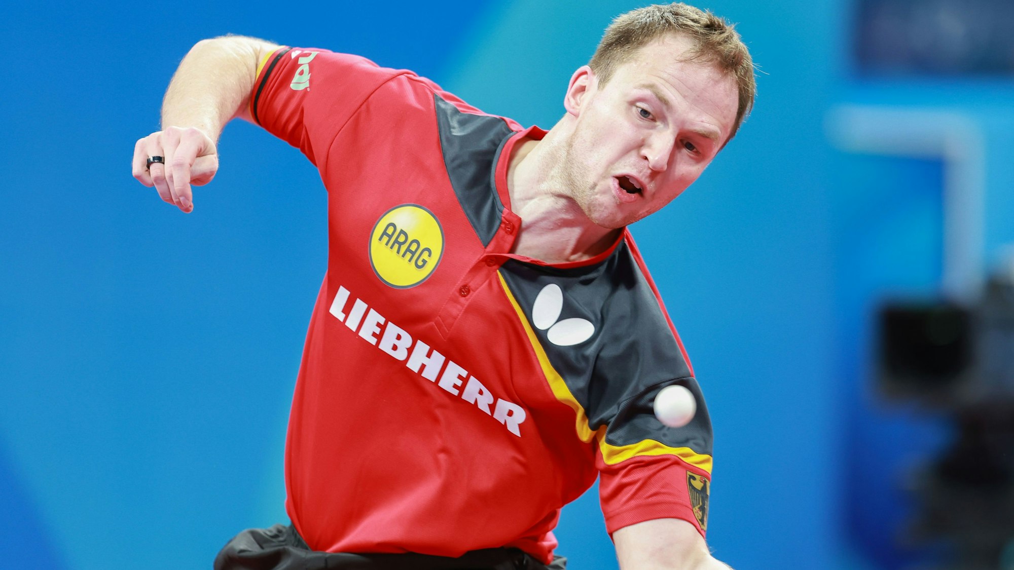 Im Bild ist ein Tischtennisspieler zu sehen, der gerade einen Ball annimmt.