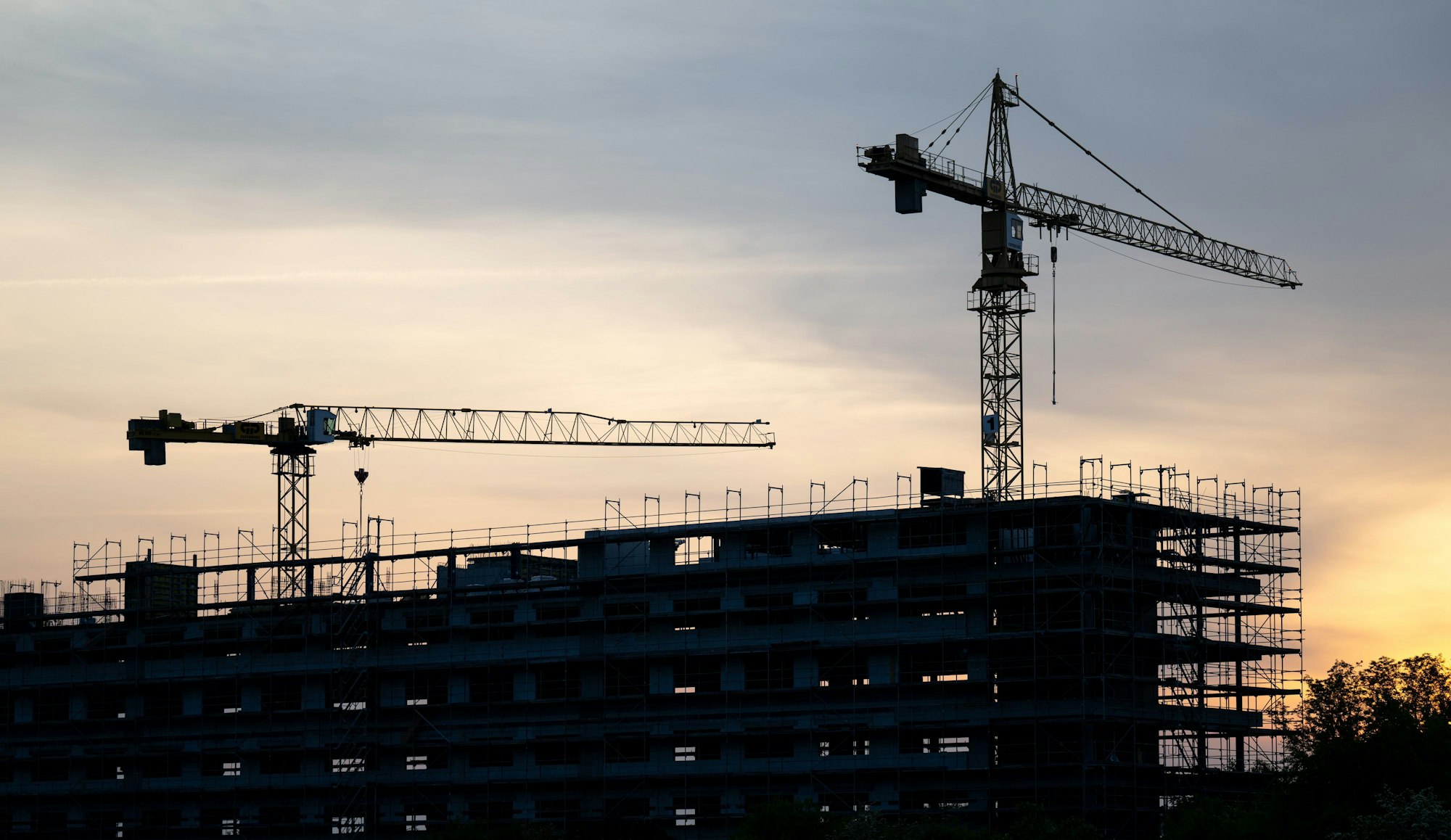 22.05.Kräne stehen hinter dem Rohbau für ein Bürogebäude auf einer Baustelle.