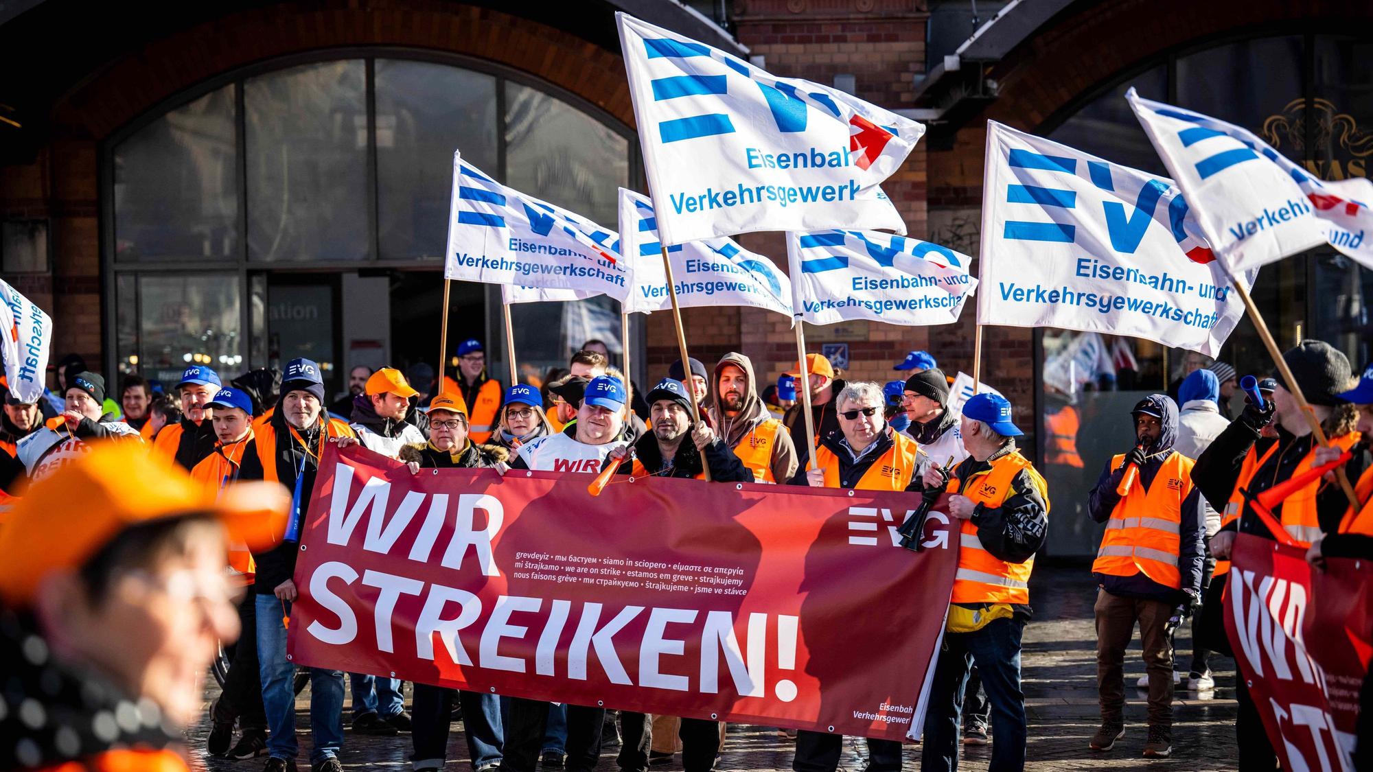 Demonstrierende der Eisenbahn- und Verkehrsgewerkschaft (EVG) protestieren am 27. März mit Plakaten vor dem Bremer Hauptbahnhof. Seit Monaten streiten die Gewerkschaft und die Deutsche Bahn um die Löhne.