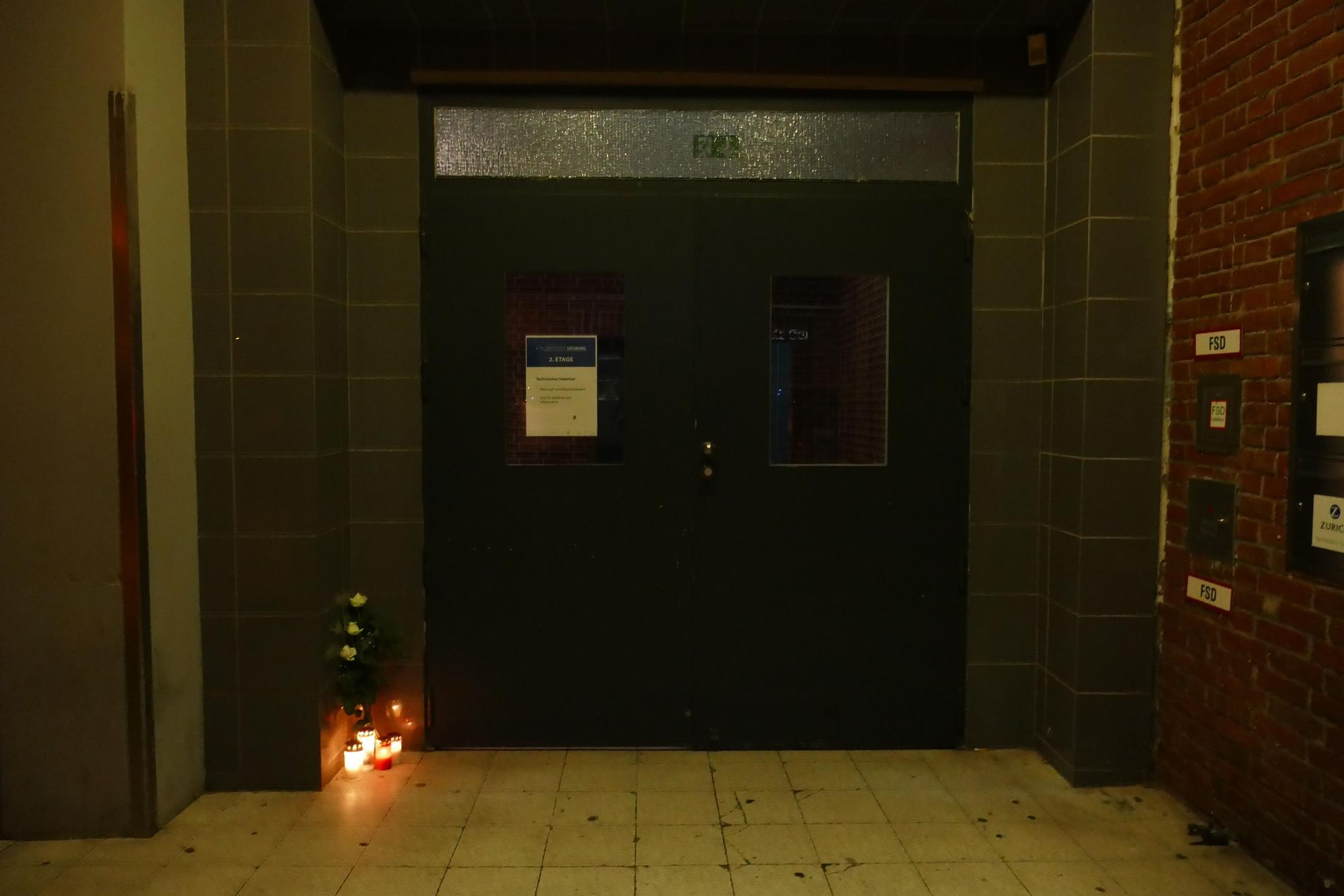 Kerzen stehen vor der Eingangstür einer Diskothek.