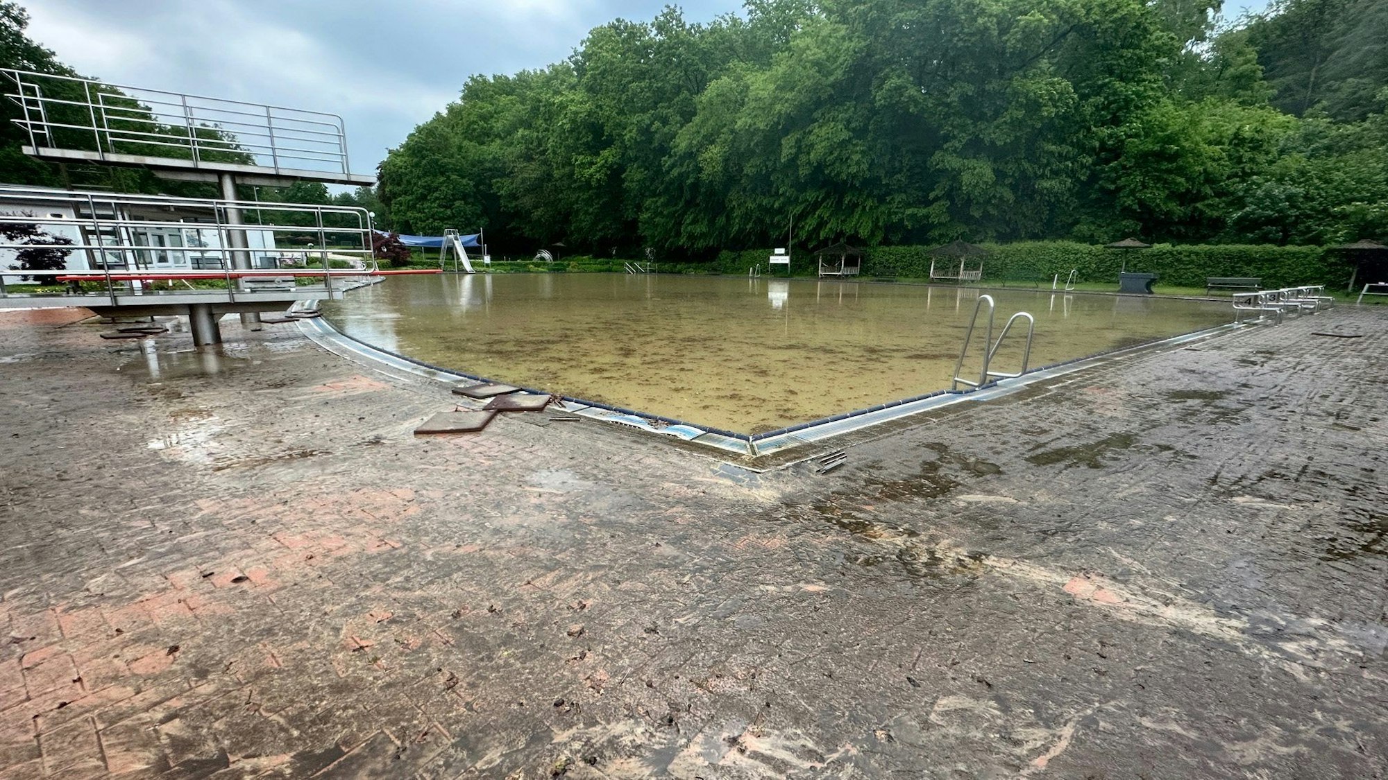 Unwetter auch in Fröndenberg: Nach heftigen Regenfällen ist das Schwimmbad „Löhn-Bad“ voller Schlamm, im Becken schwimmen Blätter.