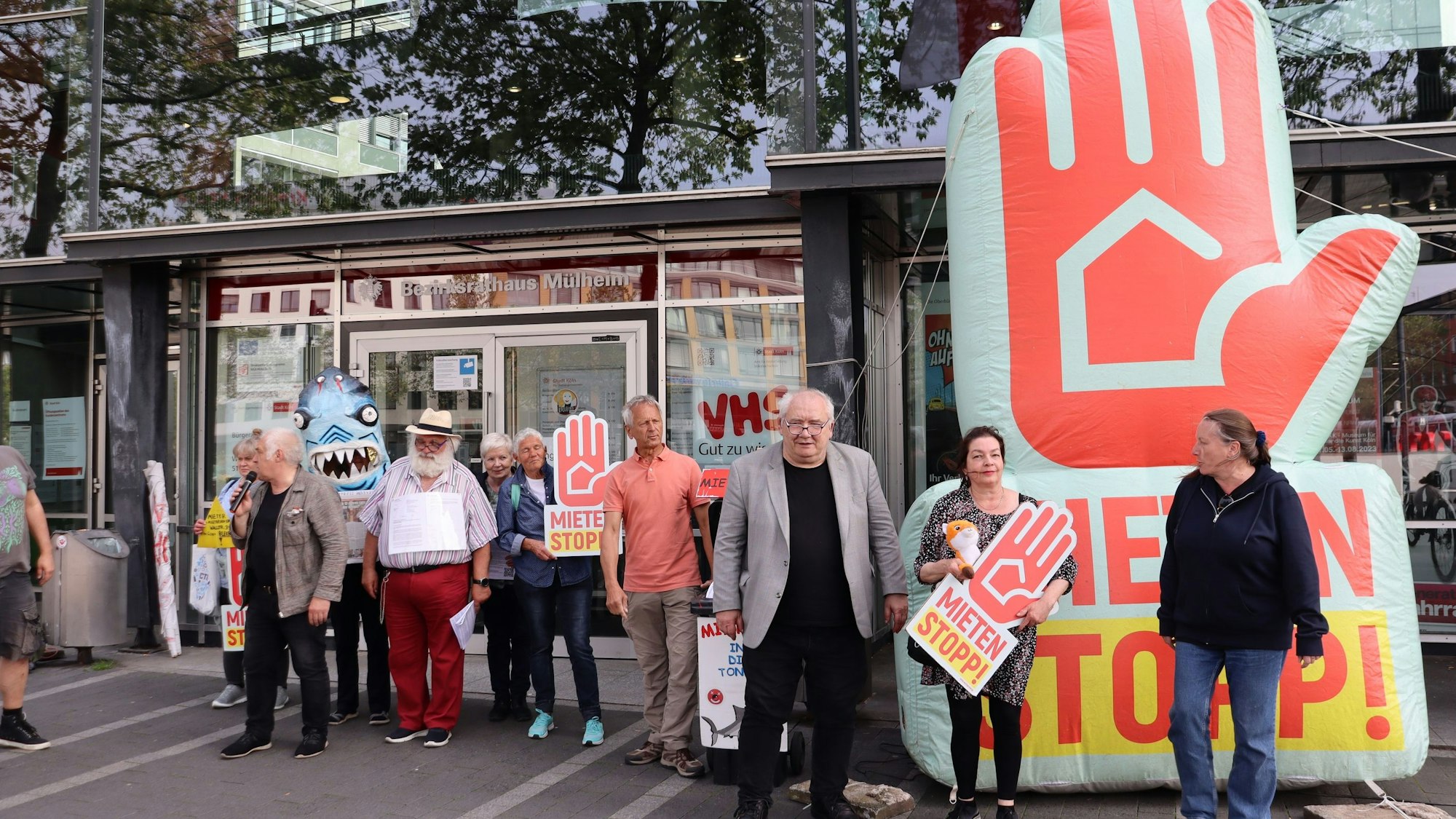 Menschen mit Plakaten stehen vor einem Flachbau.