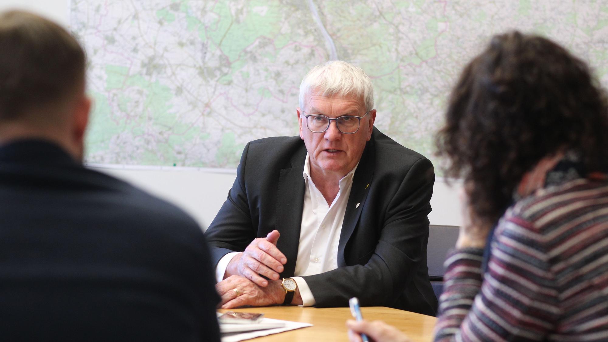 Ein Mann im Anzug ist im Gespräch mit zwei Redakteuren.