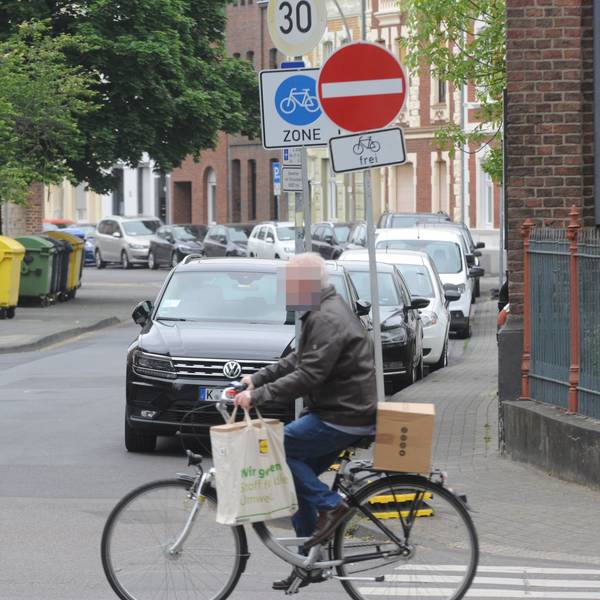Die Fahrradzone in der Frechener Innenstadt. Ein Mann fährt auf einem Fahrrad über die Straße. Im Hintergrund markiert ein Schild die Fahrradzone.