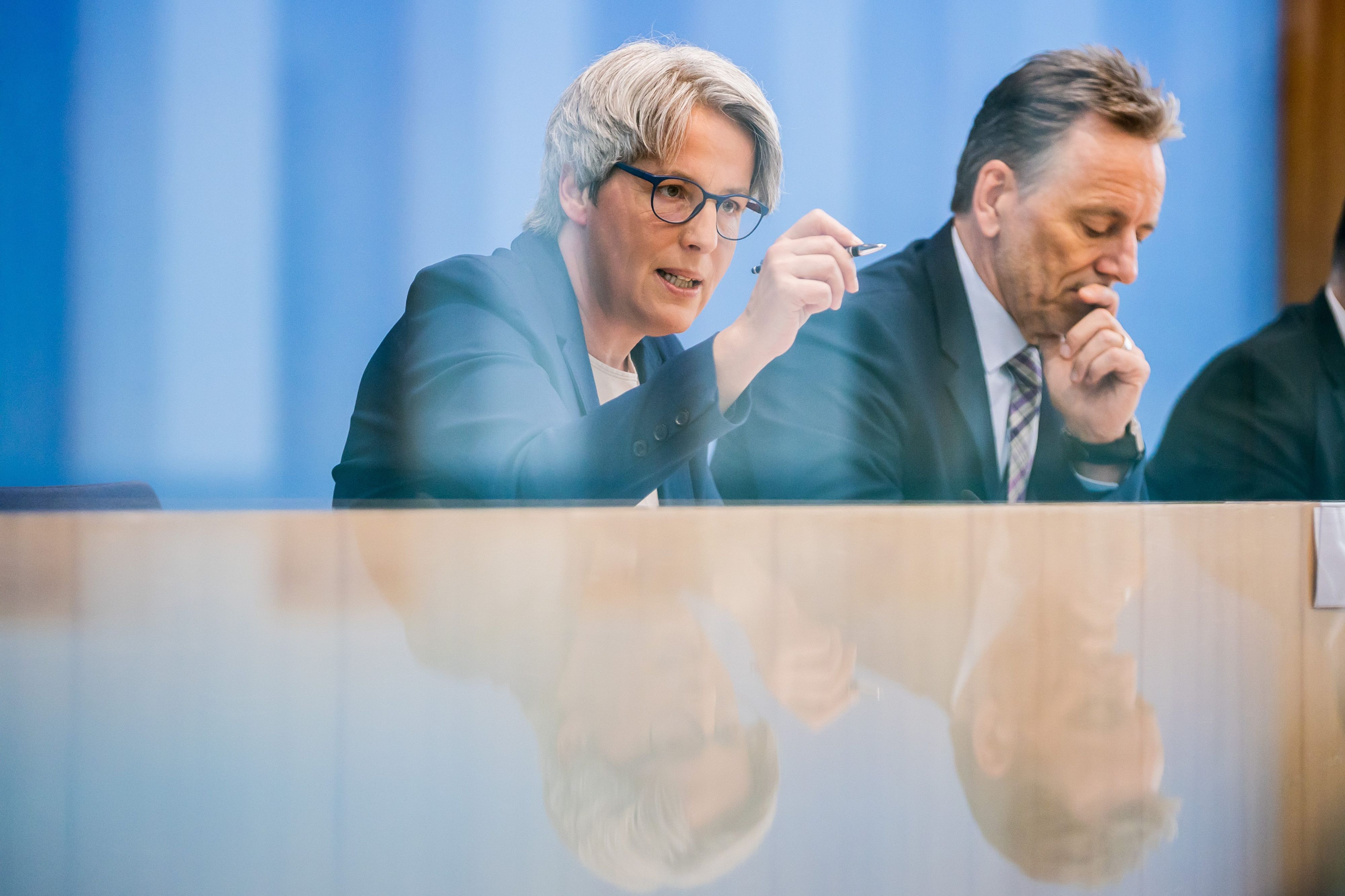 Eine Frau mit Brille und ein Mann werden auf einem Pult gespiegelt.