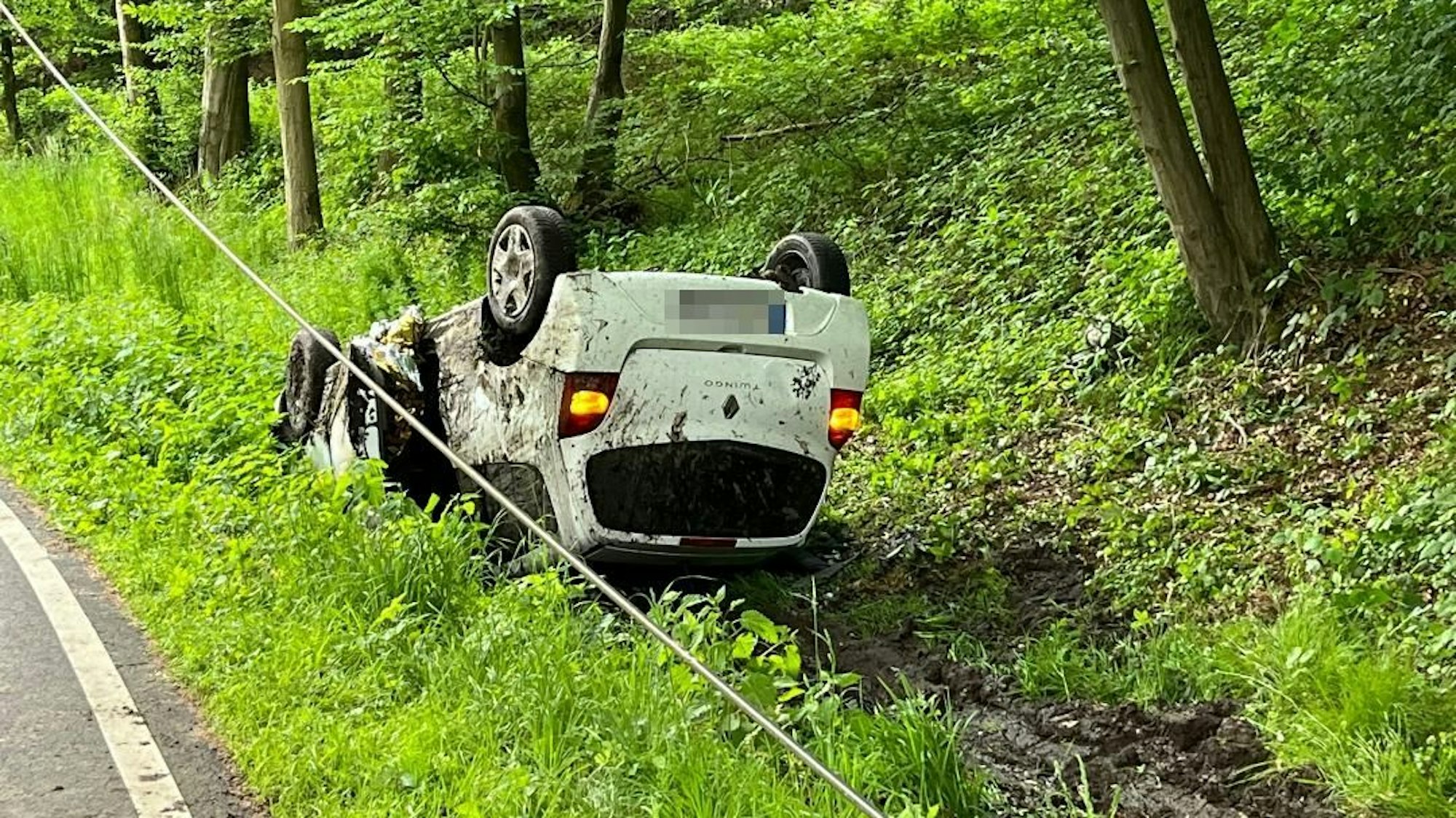 Ein weißes Auto liegt auf dem Dach im Graben.