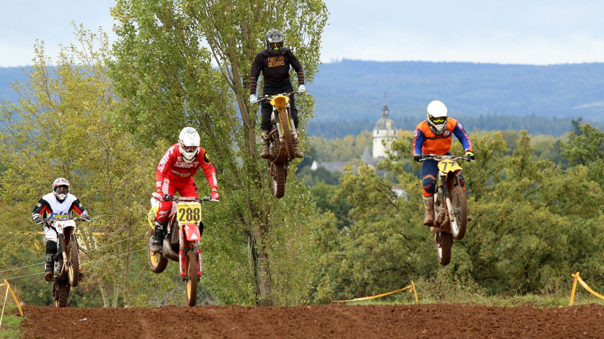 Bei einer Motocross-Veranstaltung des MSC Wißkirchen am Rosenbusch in Satzvey fliegen Motorradfahrer über die Strecke.