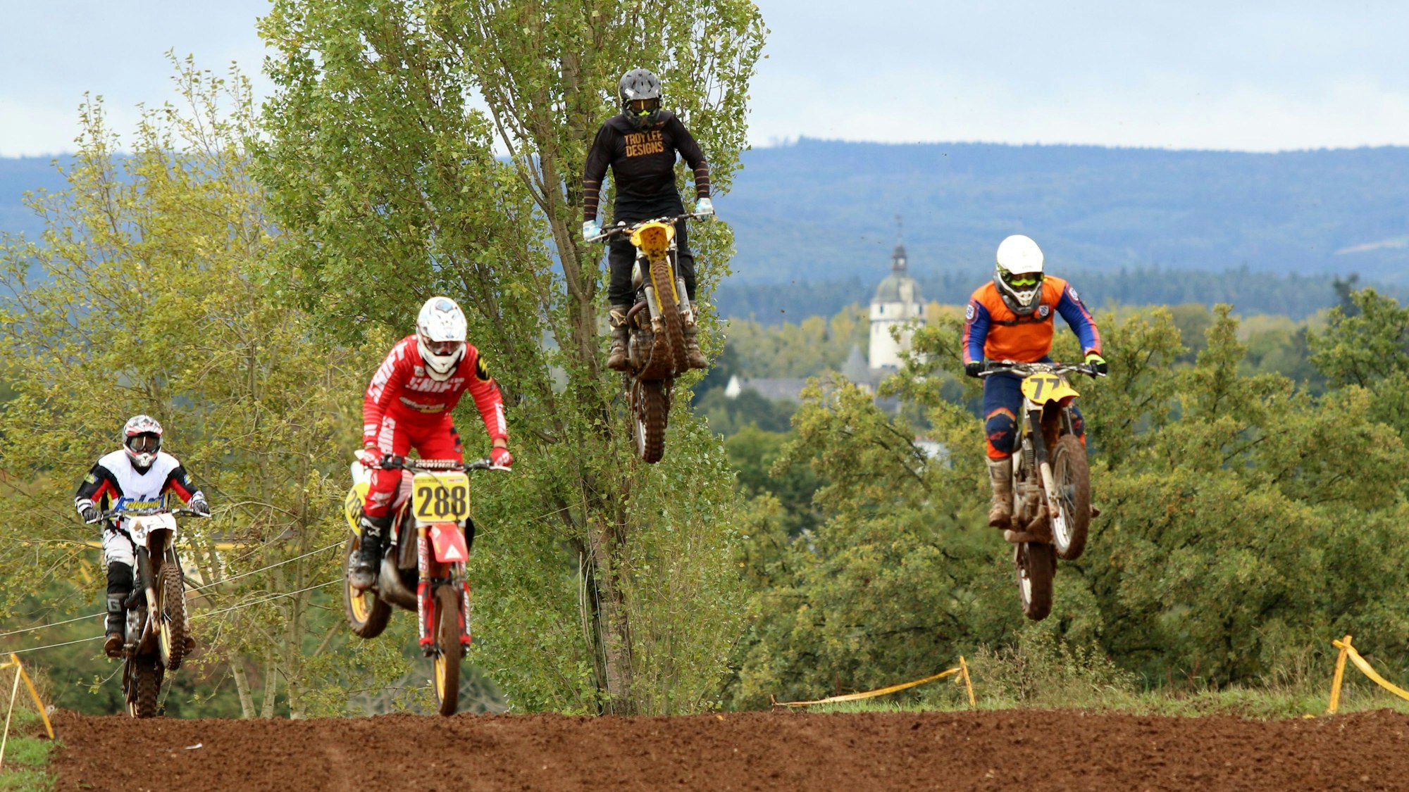Bei einer Motocross-Veranstaltung des MSC Wißkirchen am Rosenbusch in Satzvey fliegen Motorradfahrer über die Strecke.