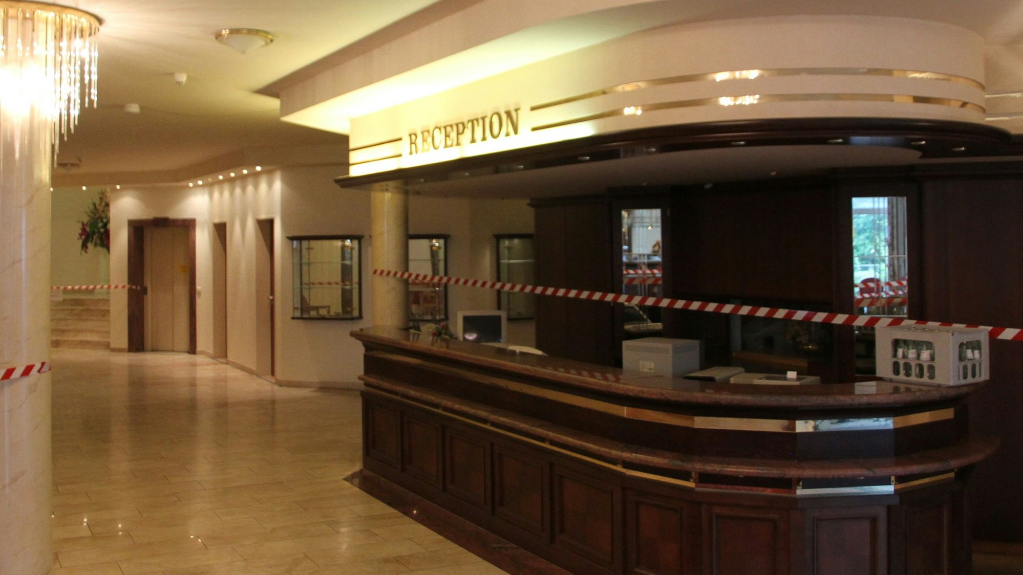 Das Hotelfoyer des Waldhotels Grunge mit der Rezeption und einem Kronleuchter