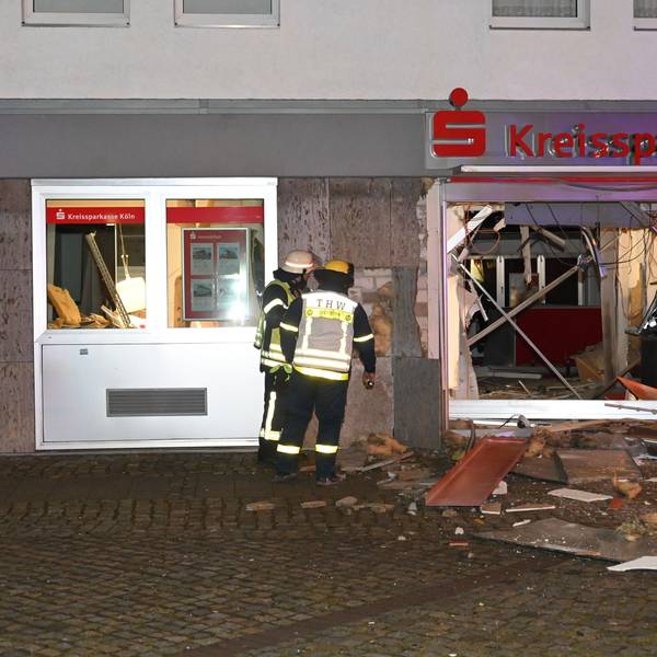 Feuerwehrleute stehen vor dem völlig zerstörten Eingangsbereich der Kreissparkasse in Kerpen-Türnich.