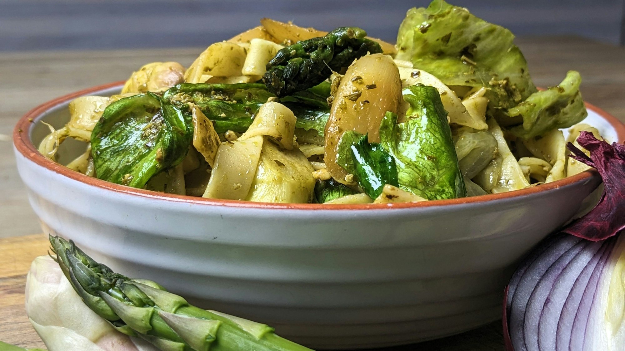 In einer Schüssel ist Paste mit Spargel und Eisbergsalat.