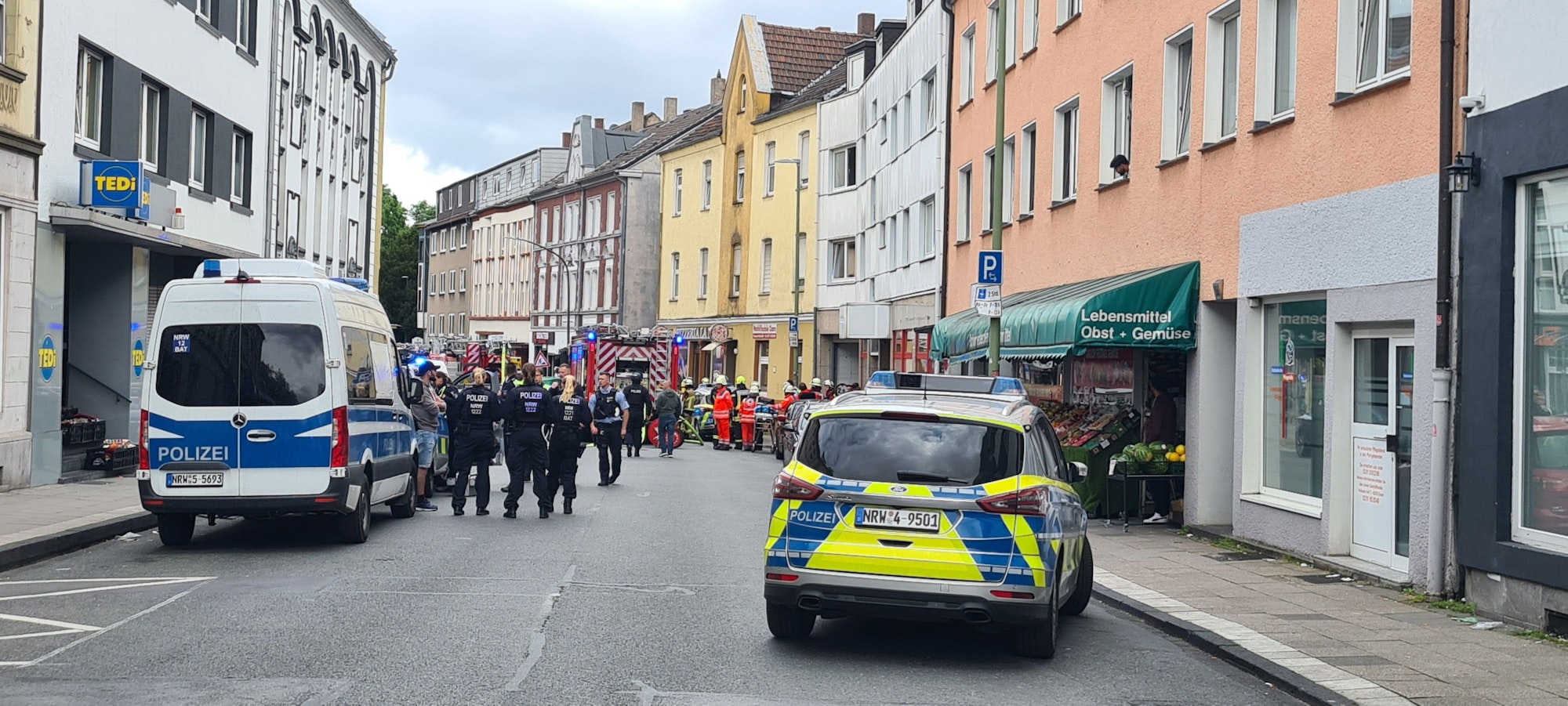 24.05.2023, Nordrhein-Westfalen, Essen: Einsatzkräfte von Feuerwehr und Polizei stehen in einer Straße in Essen-Katernberg. Ein Mann hat am Mittwochmorgen auf den Besuch einer Gerichtsvollzieherin aggressiv reagiert, eine unbekannte Flüssigkeit im Flur verschüttet und mit dem Entzünden gedroht.