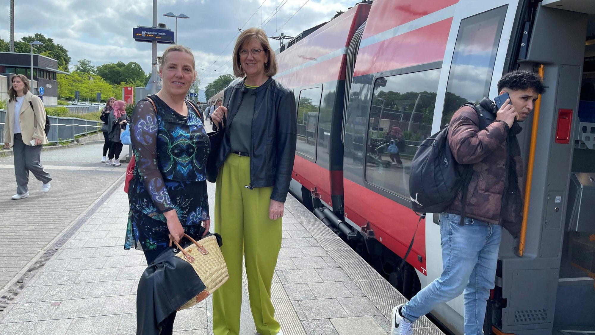 Zwei Frauen stehen vor einem einfahrenden Regionalzug.