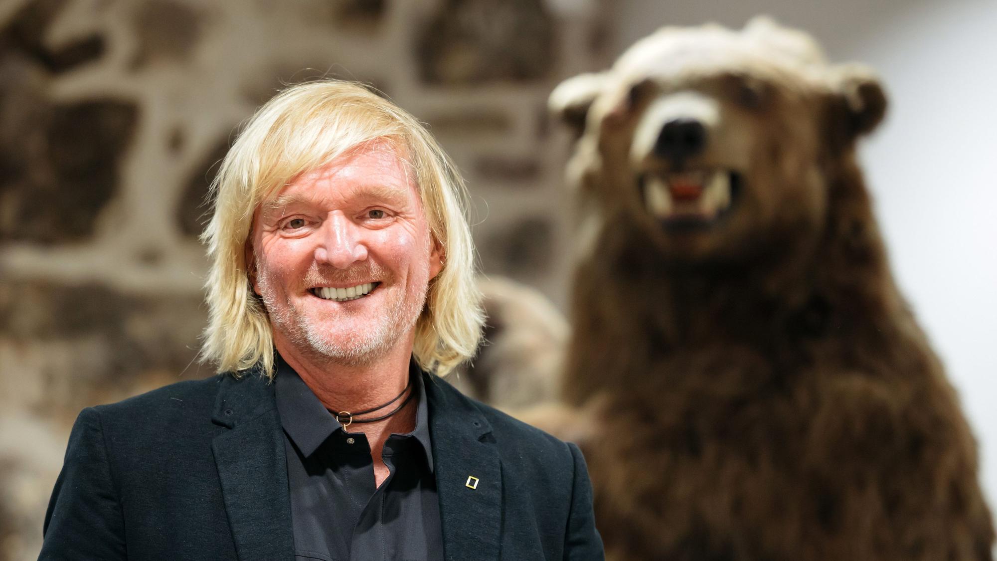 Andreas Kieling, Naturfotograf und Tierfilmer, steht neben einem ausgestopften Grizzlybären.