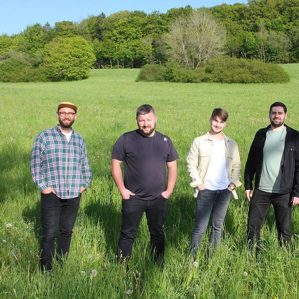 Das Bild zeigt die fünf jungen Musiker der Band „Amie & Me“ auf einer grünen Wiese.