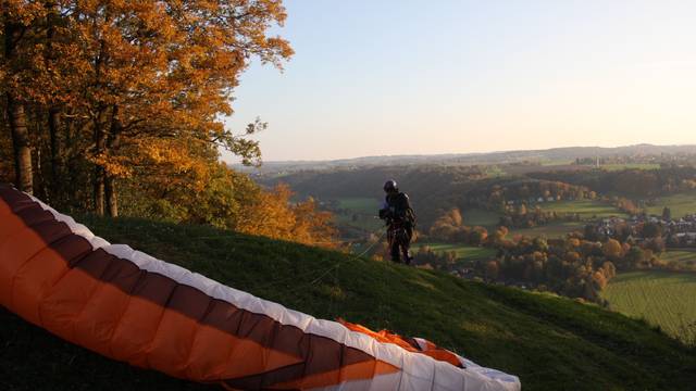 Ein Paraglider landet auf einem Hügel.
