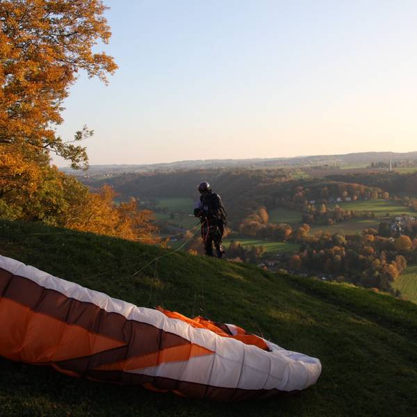 Ein Paraglider landet auf einem Hügel.