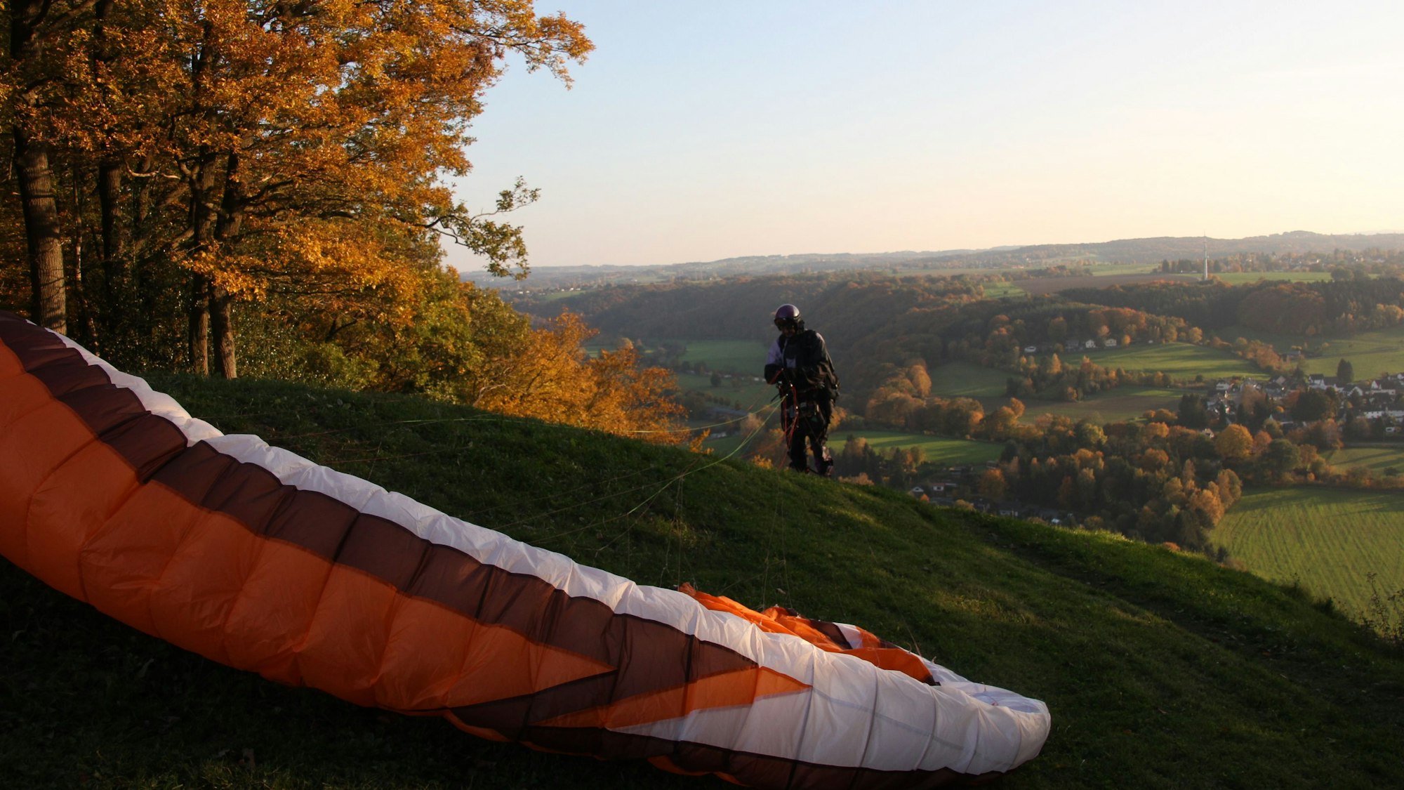 Ein Paraglider landet auf einem Hügel.