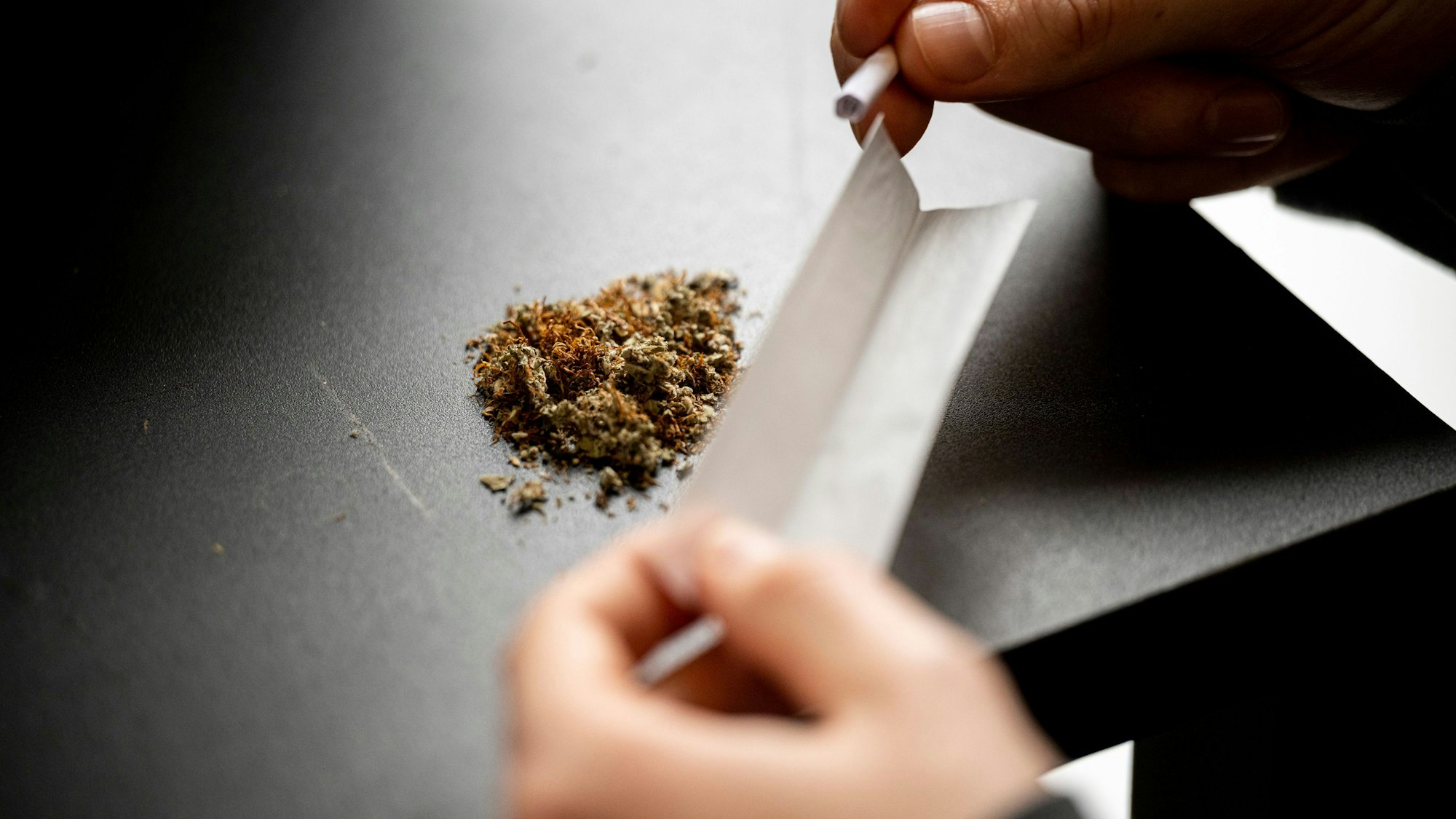 Zwei Hände drehen einen Joint.