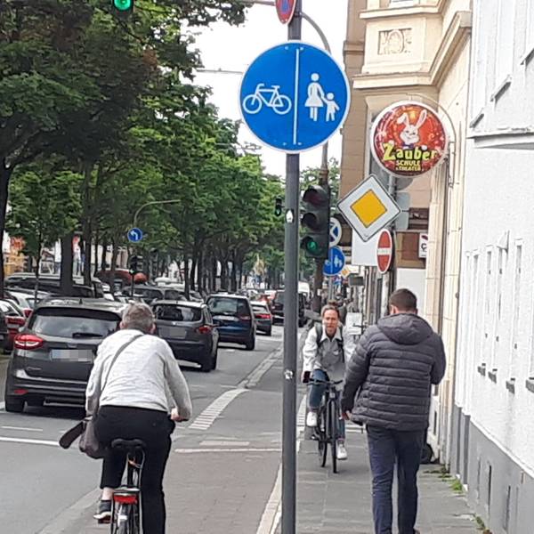 Fahrradfahrer und Fußgänger, die sich auf einem engen Rad- und Fußweg entgegen kommen,