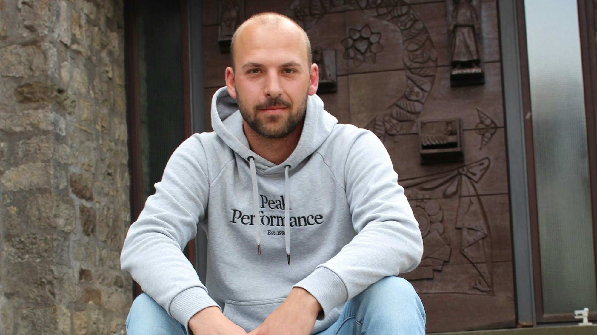 Das Bild zeigt Andreas Winkler, der auf den Stufen vor der Kirche in Marmagen sitzt.