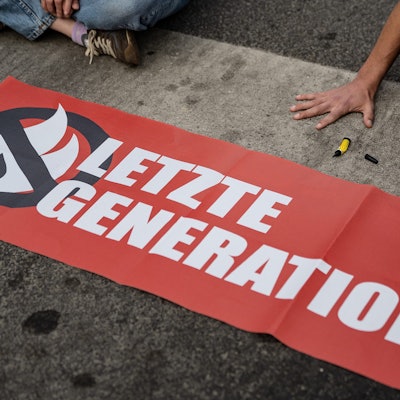Ein Aktivist der Gruppe „Letzte Generation“, der seine Hand selbst auf der Straße festgeklebt hat, blockiert eine Kreuzung am Geismar Tor.