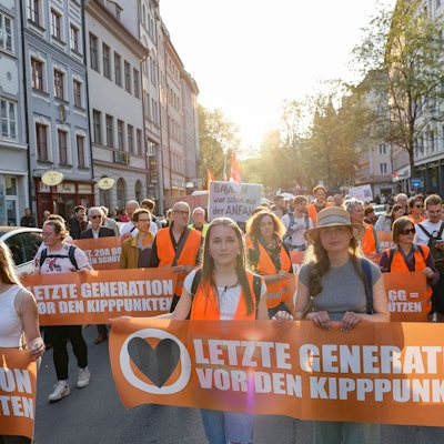 Teilnehmer gehen beim Protestmarsch der Letzten Generation und anderer Klimaschützergruppen nach der Razzia gegen Mitglieder der Klimagruppe in München die Straße entlang.