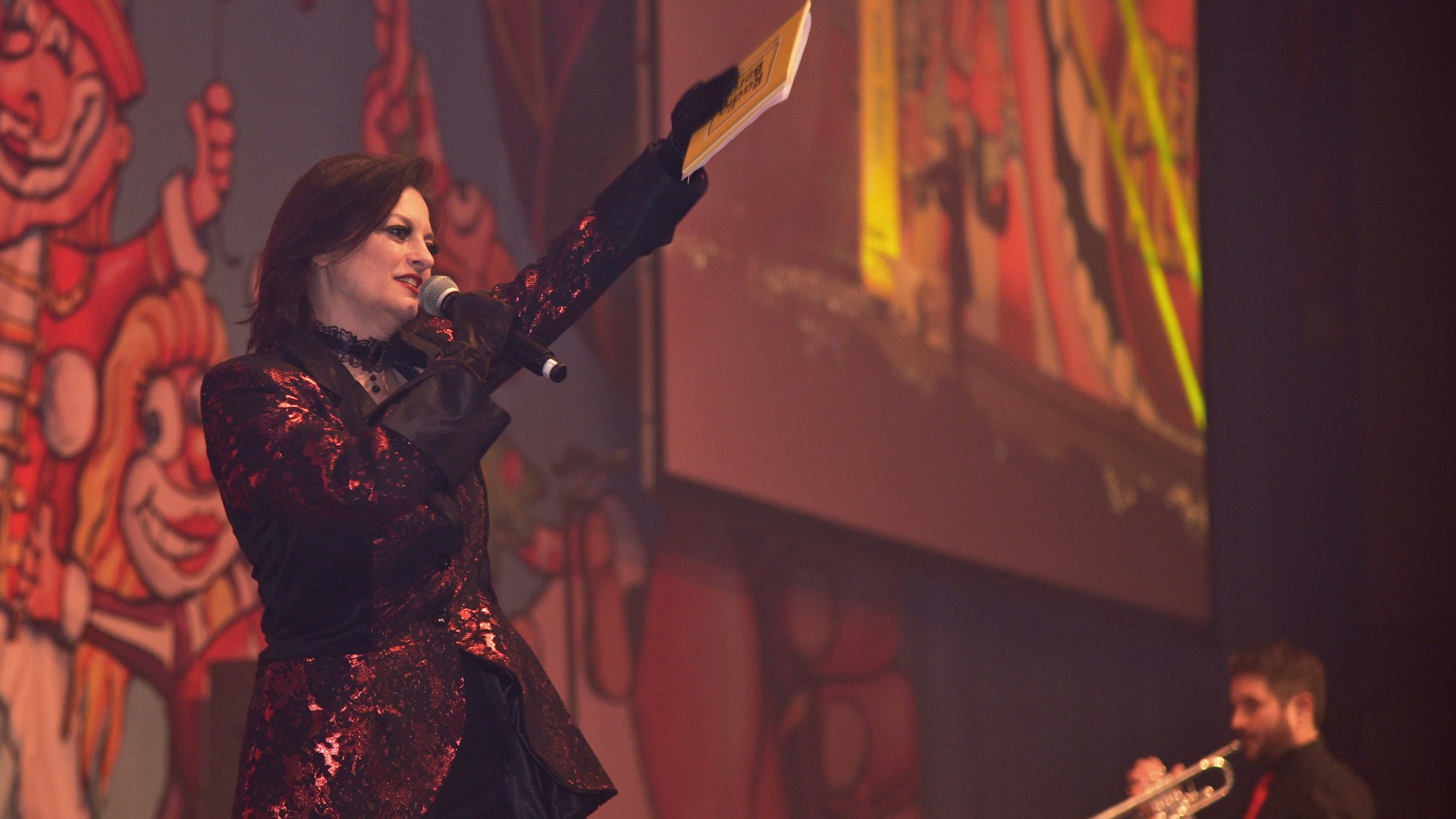 Eine verkleidete Moderatorin steht bei einer Karnevalsveranstaltung auf der Bühne.