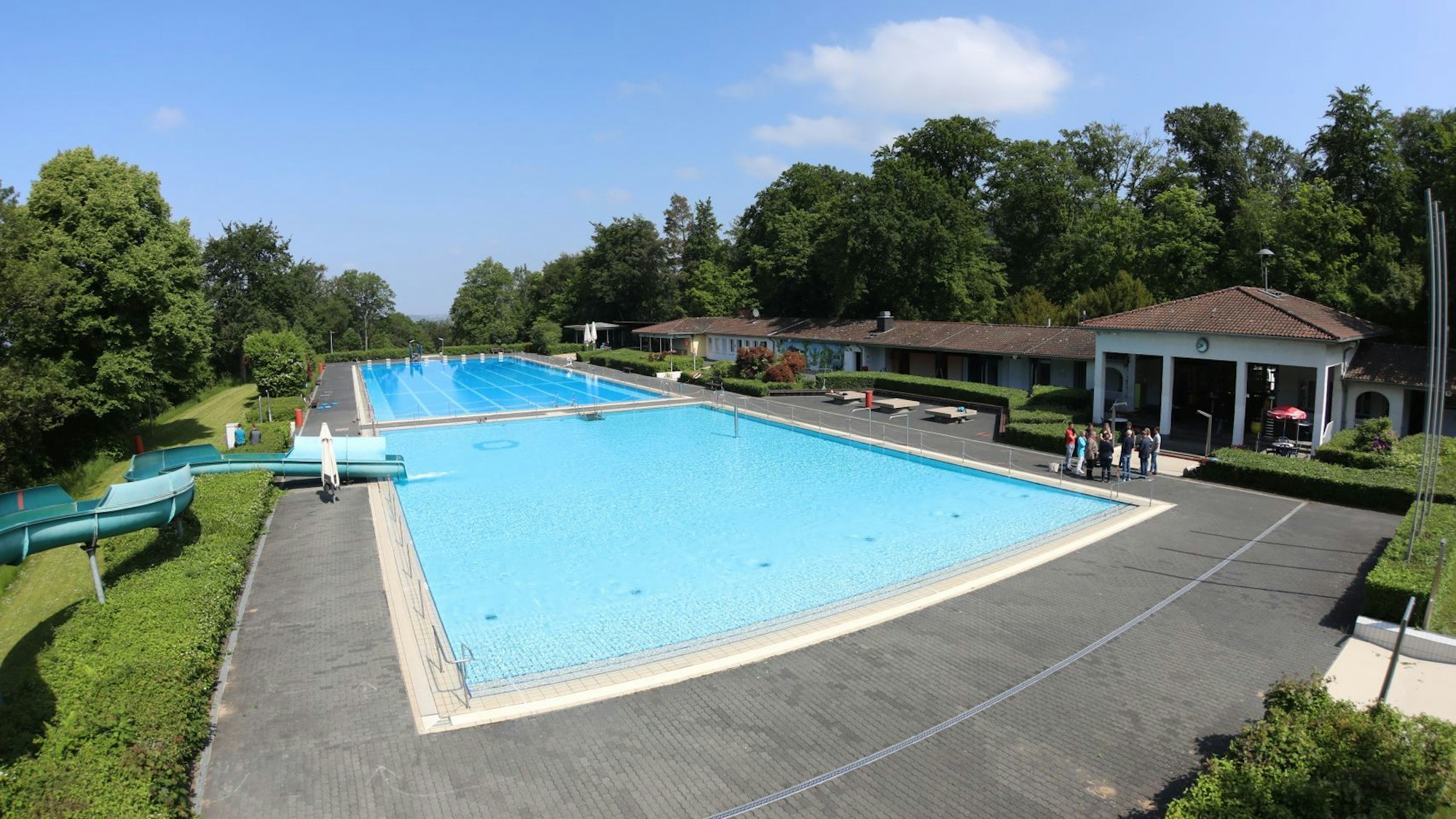 Ein Freibad mit zwei großen Becken und einer Rutsche.