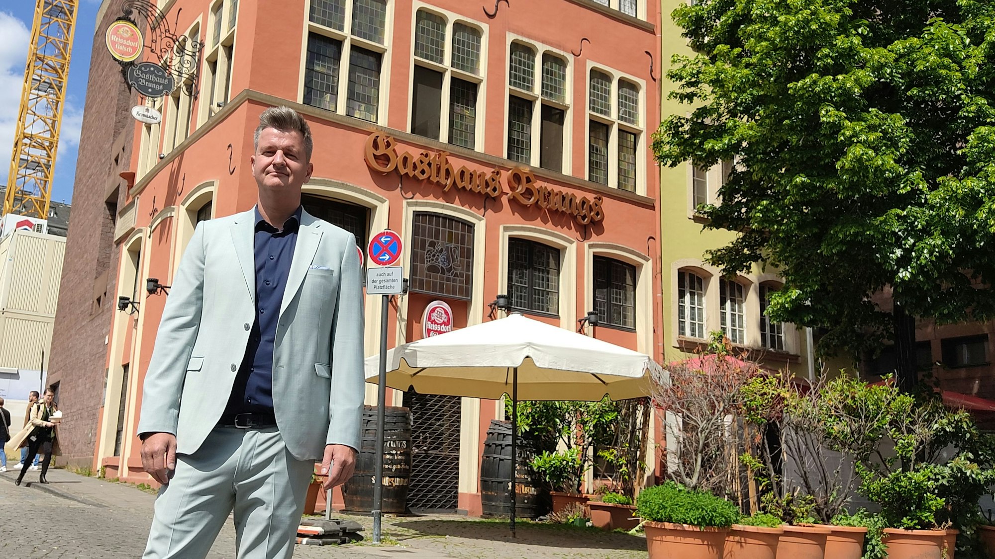 Patrick Höppener steht vor dem orangen Gebäude des Weinhaus Brungs.