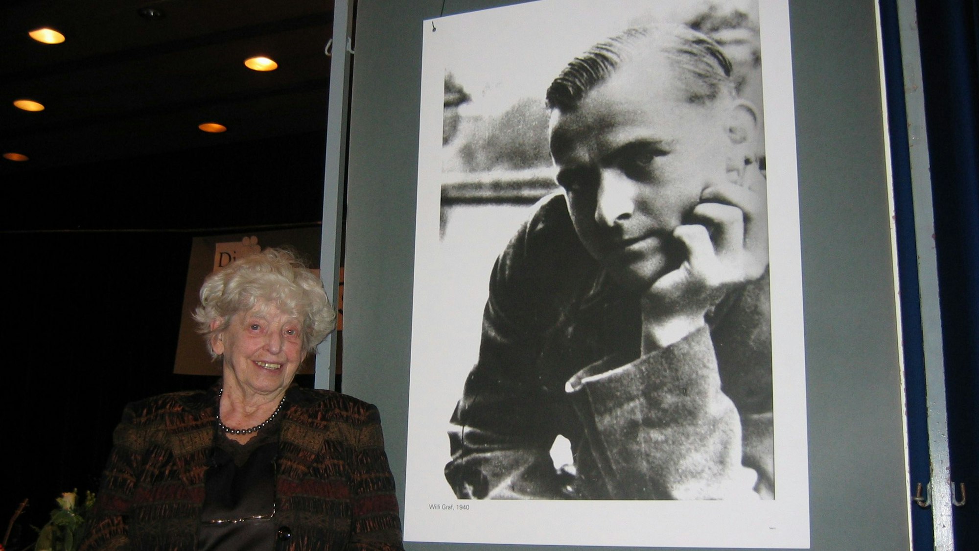 Das Foto zeigt eine Frau vor einer Schwarz-Weiß-Fotografie.