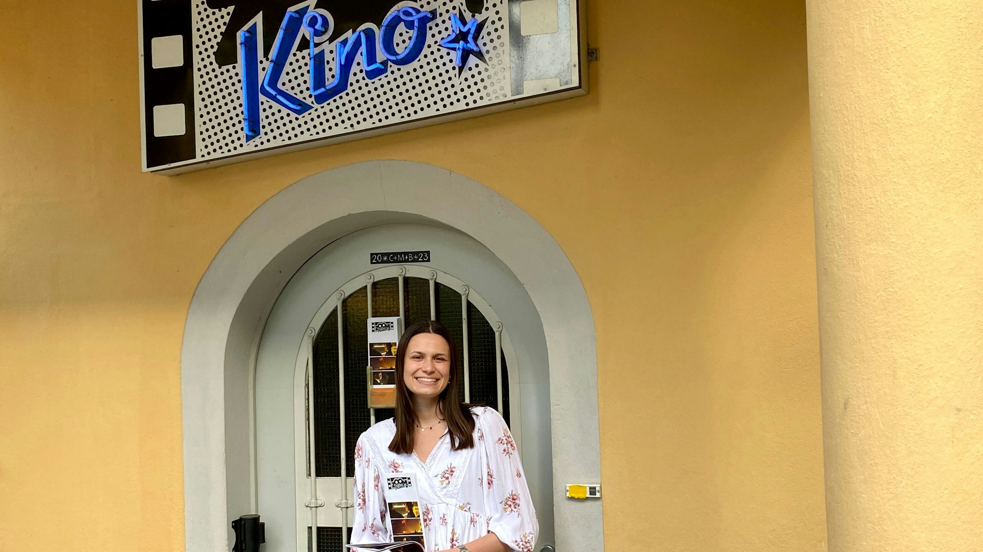 Julia Liebig steht vor dem Eingang des Brühler Zoom-Kinos. Sie hält ein Programm in den Händen.
