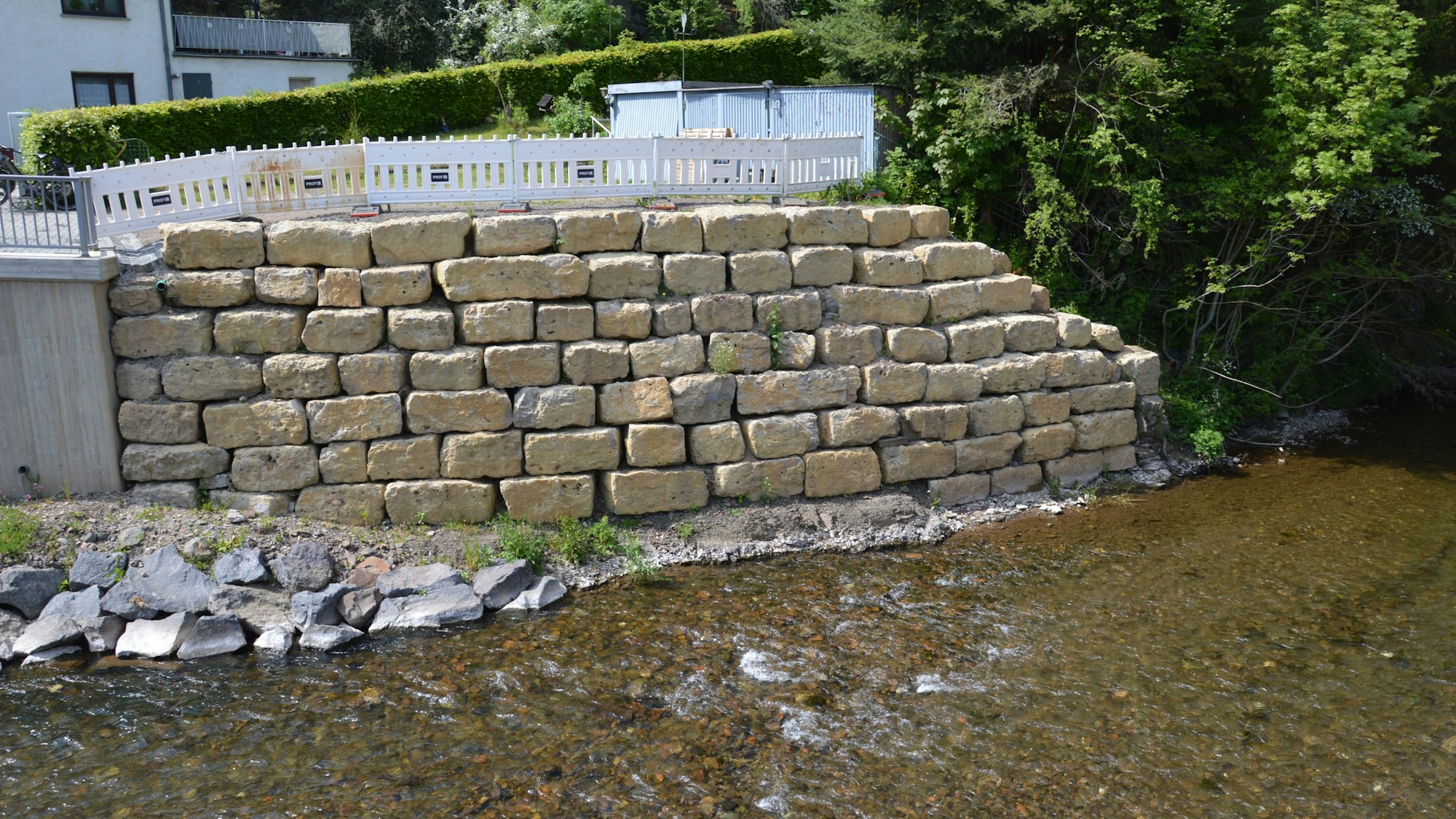Die steile Uferböschung an einer Seite der Brücke wurde mit einer großen Mauer aus schweren Steinen gesichert.