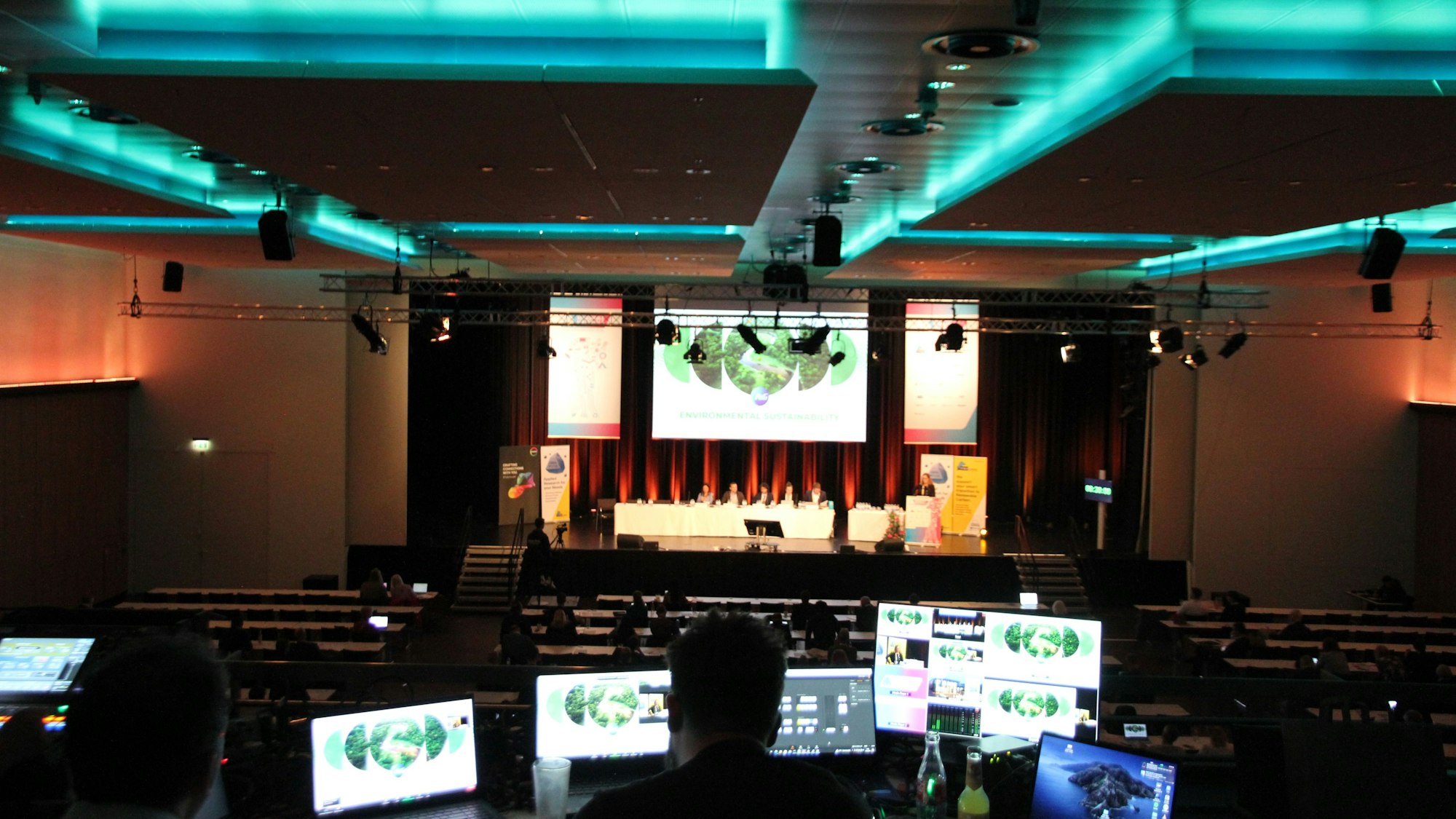 Ein Mann sitzt vor mehreren Bildschirmen in einem abgedunkelten Saal.