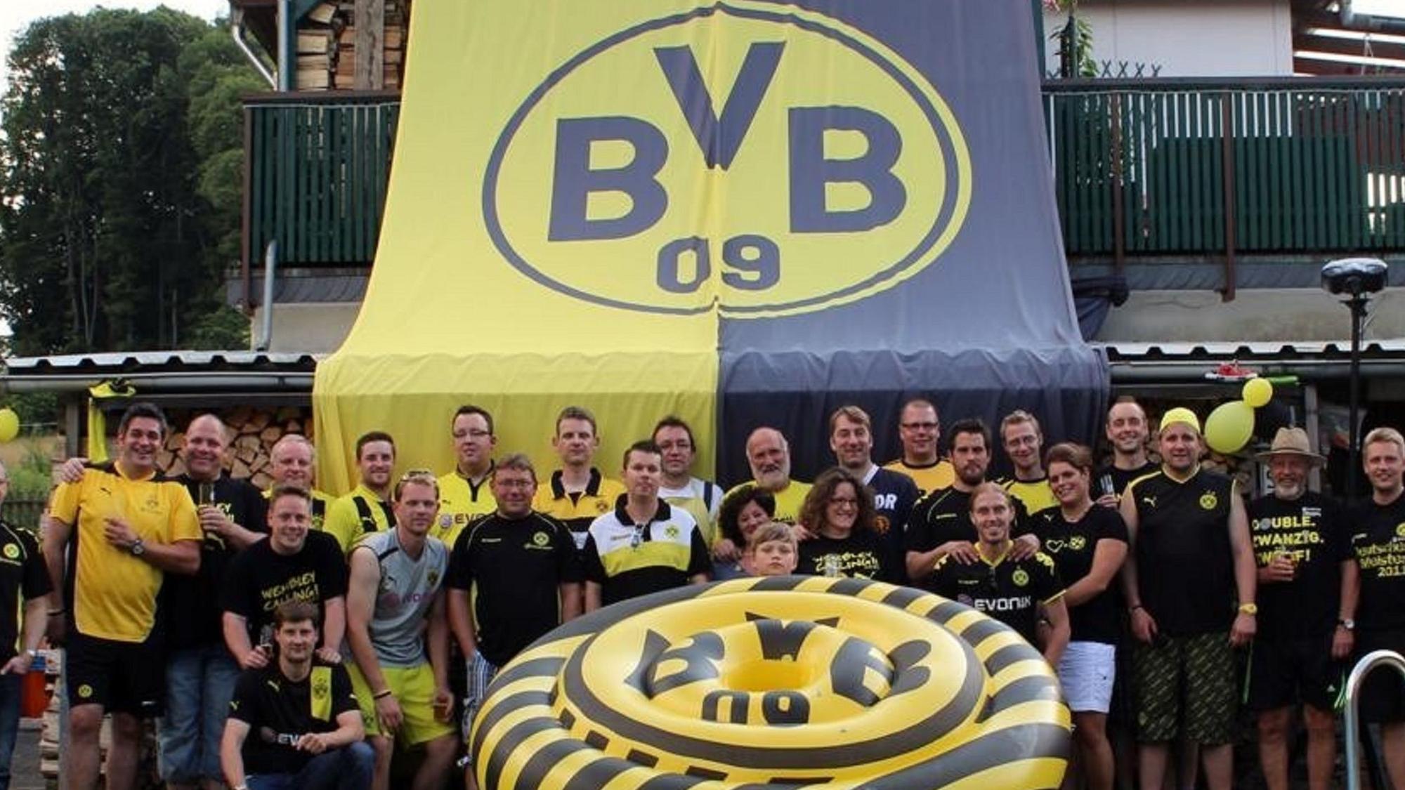 Der Fanklub „Die Gefolgschaft“ mit seinen Mitgliedern vor einer großen BVB-Fahne.