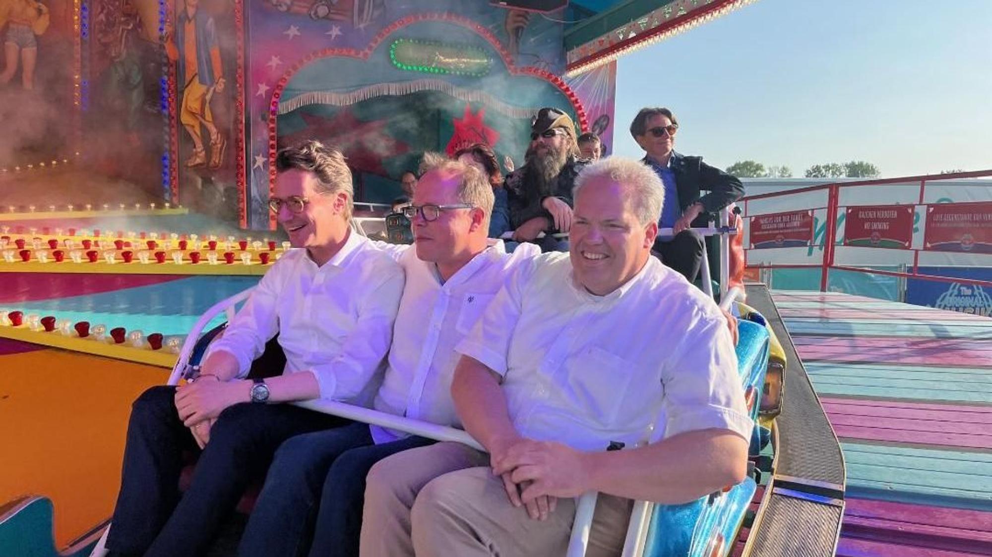 Der Männer fahren auf einer Kirmes Karussell.
