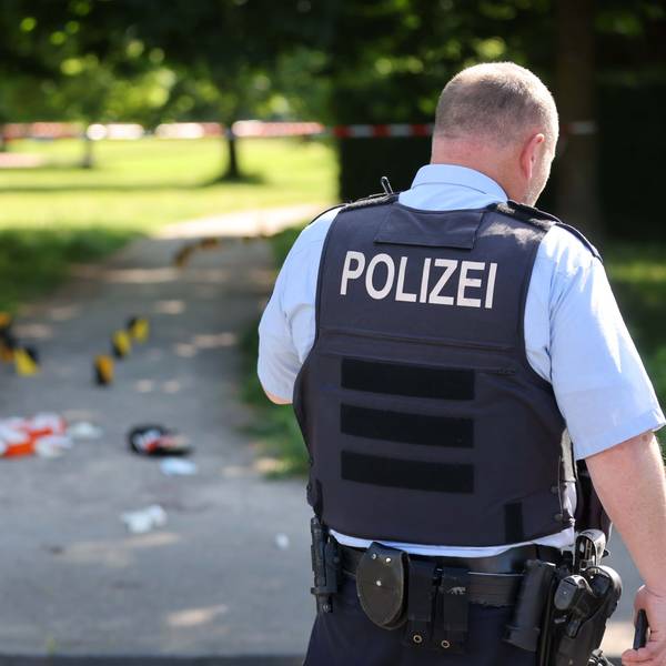 Ein Polizist überwacht den abgesperrten Bereich eines Tatorts - er steht mit dem Rücken zur Kamera.