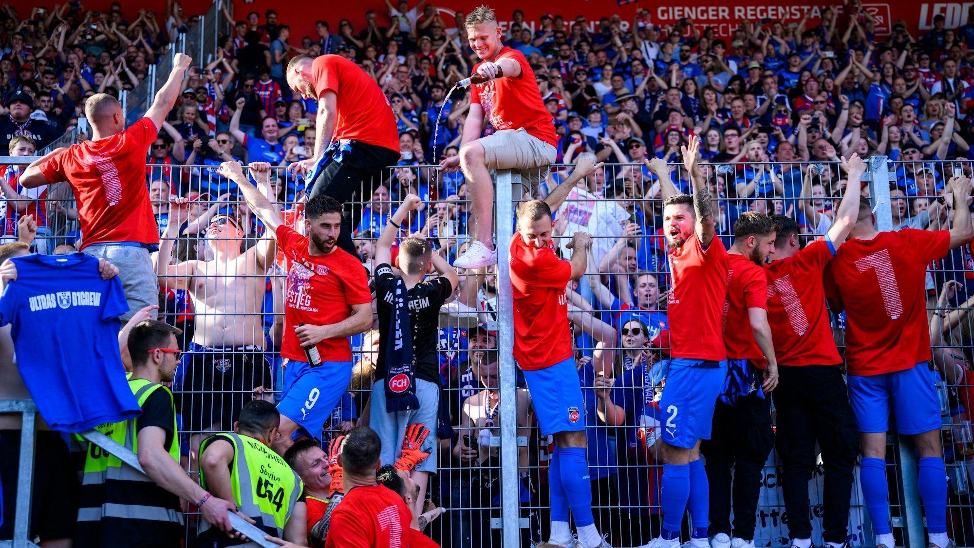 Die Spieler jubeln nach dem Spiel bei den Fans über den Aufstieg und die Meisterschaft in der 2. Bundesliga. Sie überschütten sich mit Bier.