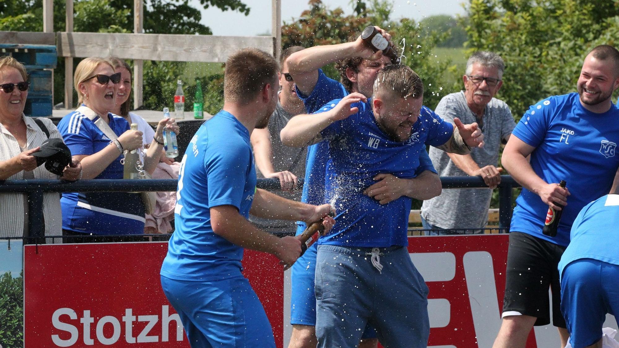 Stotzheims Trainer Wolfgang Botzian erhält von zwei Spielern eine Bierdusche.