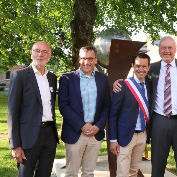 Die beiden Bürgermeister und Vertreter der Partnerschaftskomitees stehen gemeinsam vor der enthüllten Skulptur auf dem Engels-Platz.