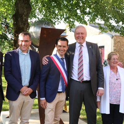 Die beiden Bürgermeister und Vertreter der Partnerschaftskomitees stehen gemeinsam vor der enthüllten Skulptur auf dem Engels-Platz.